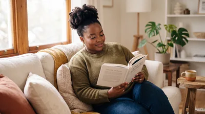 Black Woman Reading A Book On A Cozy Sofa