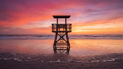Lifeguard Tower Silhouette Against A Vibrant Sunset