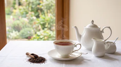 Steaming Cup Of Tea With Teapot And Loose Leaves