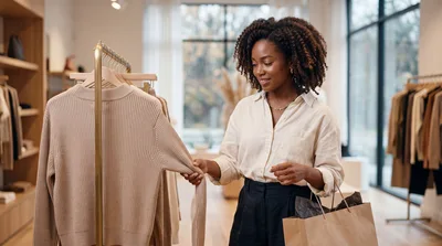 Young Woman Shopping For Sweaters In A Clothing Boutique