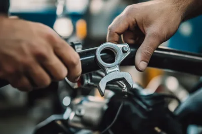 Mechanic Adjusting Motorcycle Handlebar Components In Workshop