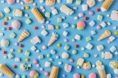 Assorted Marshmallow Candies and Waffle Cones on Blue Background