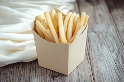 French Fries In A Paper Box On Wooden Table