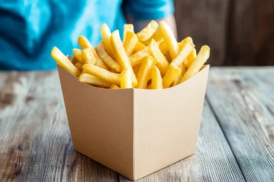 French Fries In A Cardboard Box On Wooden Table