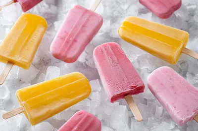 Assorted Fruit Popsicles Resting On Crushed Ice