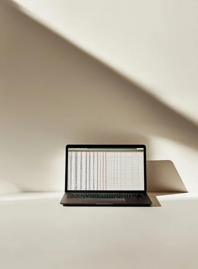 Laptop Displaying Spreadsheet Data On Minimalist Desk