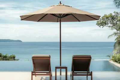 Two Lounge Chairs Under Umbrella Overlooking Tropical Ocean