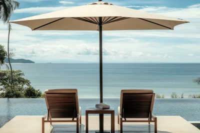 Two Lounge Chairs Under Umbrella Overlooking Tropical Ocean