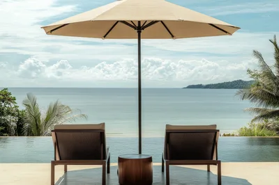 Two Lounge Chairs By An Infinity Pool Overlooking The Ocean