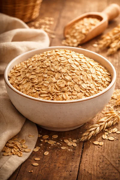 Bowl of Raw Rolled Oats on Rustic Wooden Table