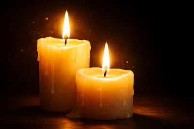 Two Lit Candles Glowing Against A Dark Background