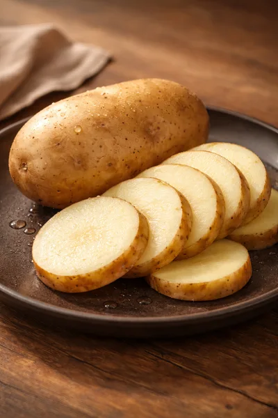 Whole And Sliced Raw Potato On A Plate