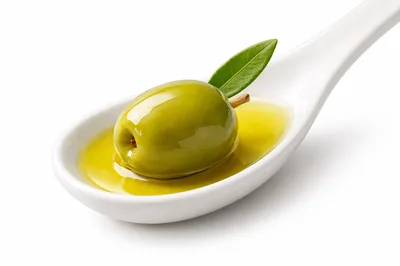 Single Green Olive With Leaf In Spoon Of Olive Oil