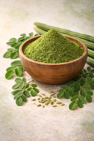 Moringa Powder in Wooden Bowl with Leaves and Pods