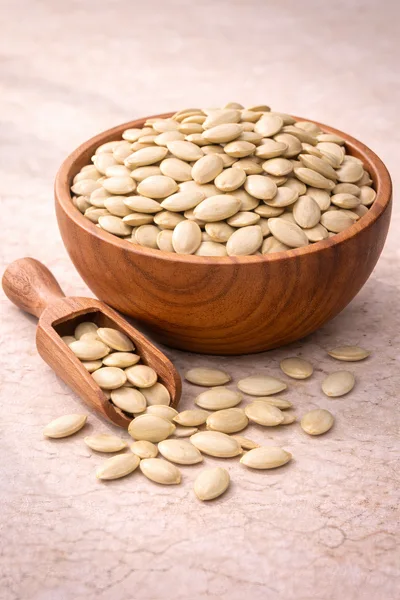 Wooden Bowl And Scoop Filled With Pumpkin Seeds