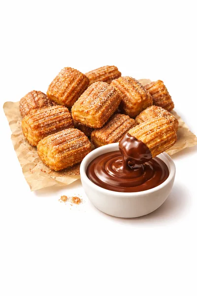 Churros Dipped In Chocolate Sauce On Parchment Paper