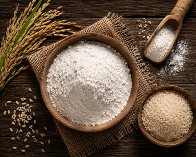 Rice Flour And Raw Rice Grains On Wooden Table