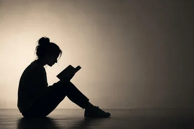 Silhouette Of A Young Woman Reading A Book