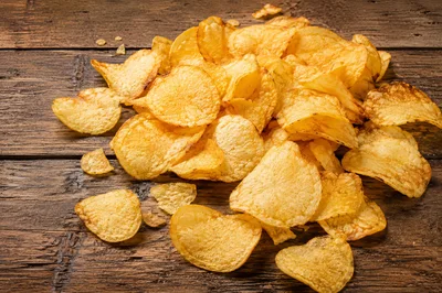 Pile Of Crispy Potato Chips On Rustic Wooden Table