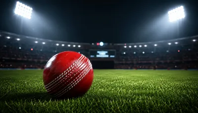 Red Cricket Ball Resting on Stadium Grass