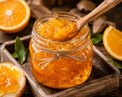 Glass Jar of Orange Marmalade with Wooden Spoon