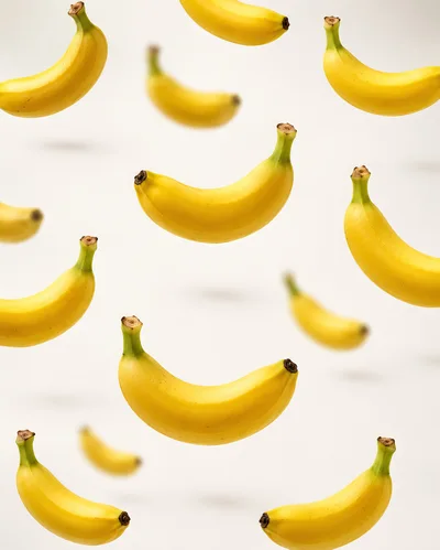 Fresh Yellow Bananas Floating Against White Background