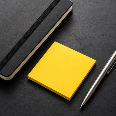Black Notebook With Yellow Sticky Note And Silver Pen