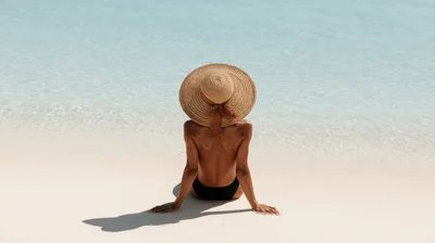 Woman Sitting On Tropical Beach Wearing Straw Hat