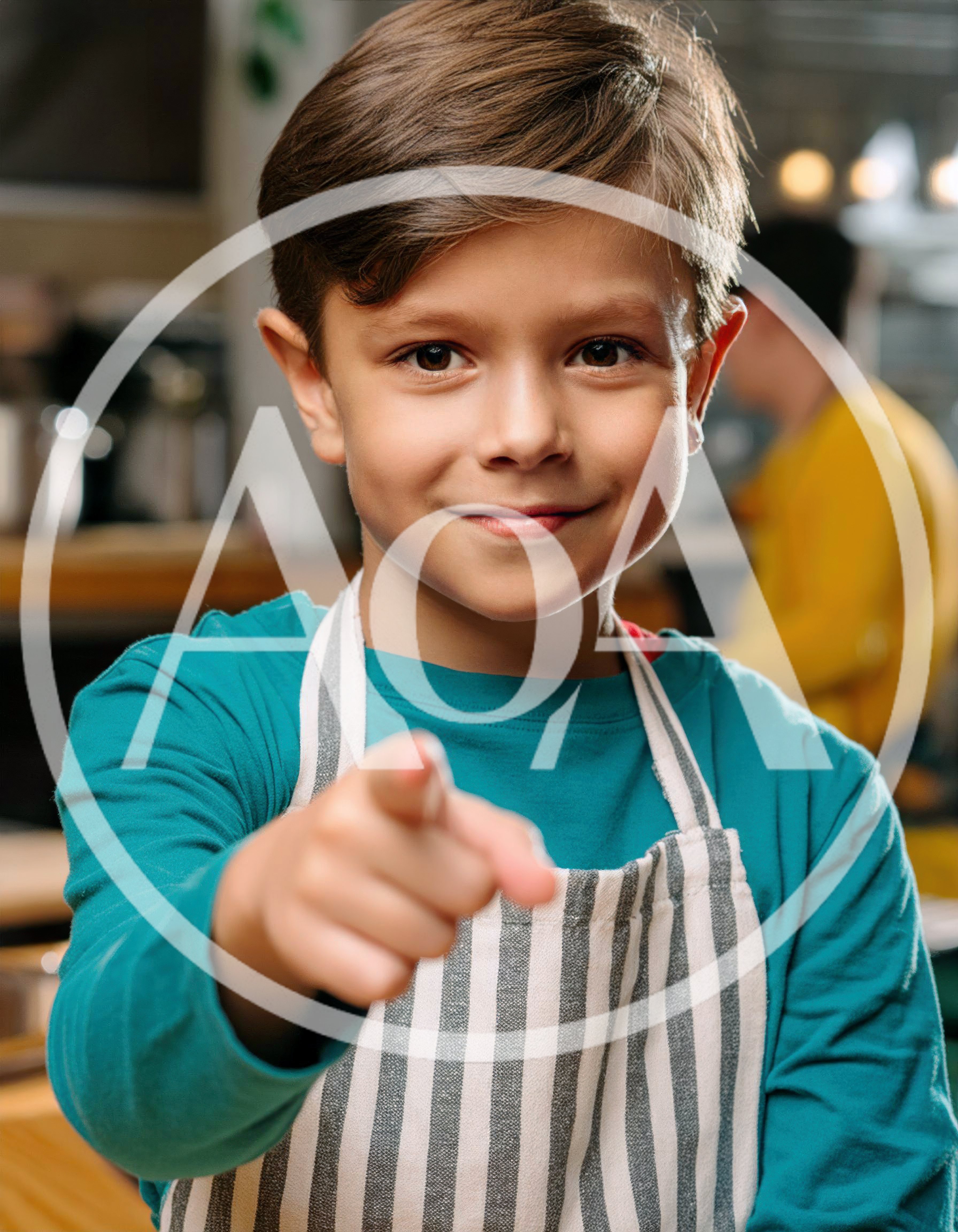 Young Boy Wearing Apron Pointing At Camera