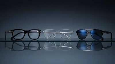 Three Pairs Of Designer Eyewear On Reflective Surface