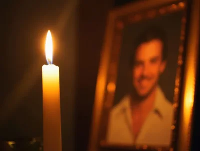 Lit Candle Beside A Framed Portrait Of A Man