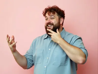 Happy Man Gesturing With Hands Against Pink Background