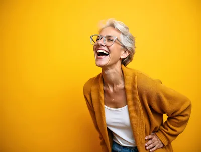Happy Mature Woman Laughing Against Yellow Background