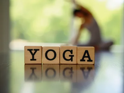 Wooden Blocks Spelling Yoga on a Reflective Surface