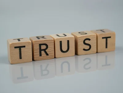 Wooden Blocks Spelling The Word Trust On Reflective Surface