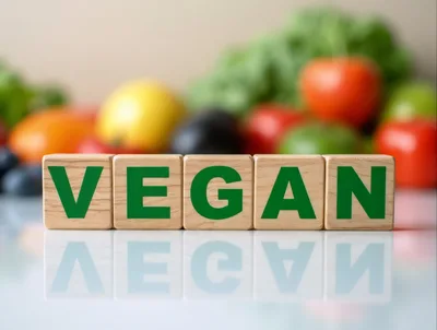 Wooden Blocks Spelling Vegan With Fresh Vegetables Background