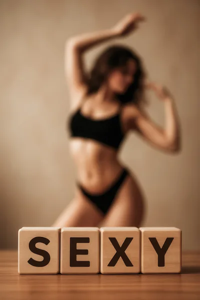 Wooden Blocks Spelling Sexy With Blurred Woman In Background