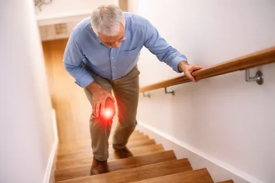 Senior Man Experiencing Knee Pain While Climbing Stairs