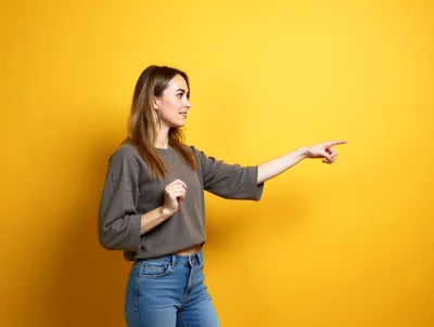 Young Woman Pointing To The Side Against Yellow Background