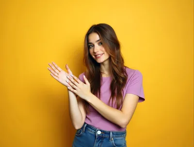 Young Woman Clapping Hands Against Yellow Background
