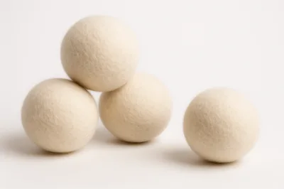 Four White Wool Dryer Balls On White Background