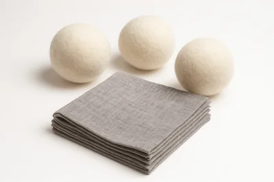 Three Wool Dryer Balls With Folded Grey Fabric Napkins