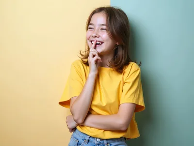 Happy Young Girl Laughing With Finger On Lips
