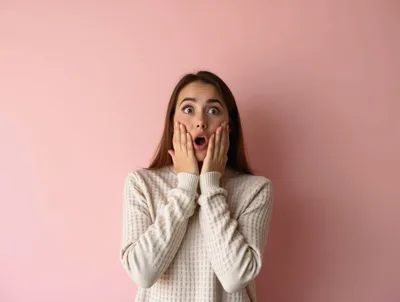 Surprised Young Woman With Hands On Cheeks