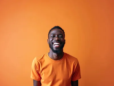 Happy Black Man Laughing Against Orange Background