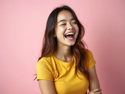 Young Asian Woman Laughing Joyfully Against Pink Background