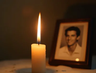 Lit Candle Beside A Framed Portrait Of A Man