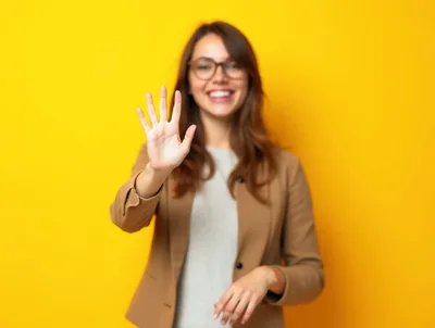 Young Woman Showing Five Fingers Against Yellow Background