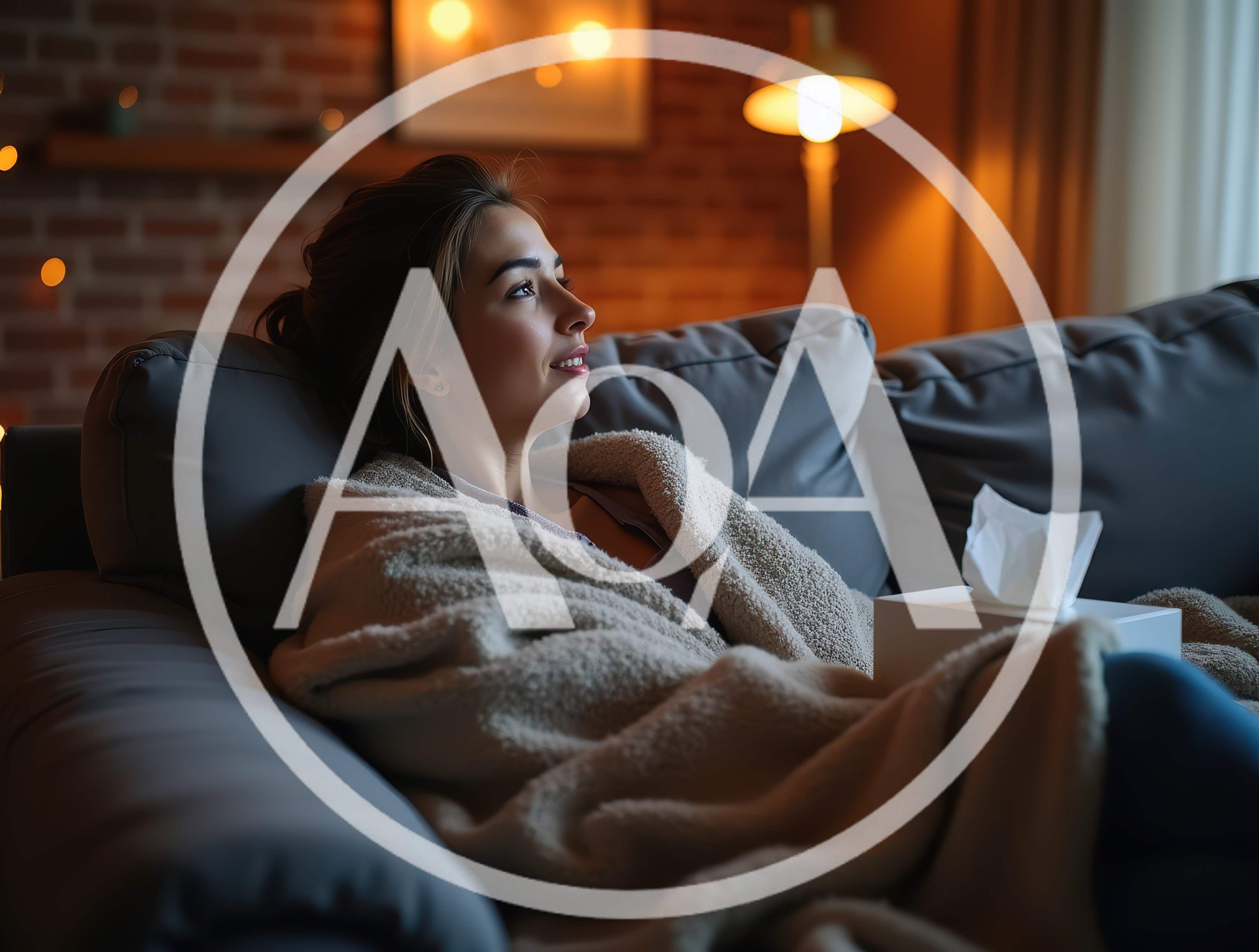 Young Woman Relaxing On Sofa With Blanket And Tissues