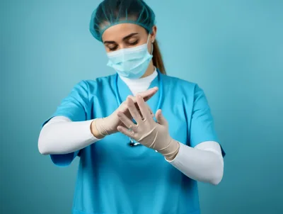 Female Healthcare Professional Putting On Sterile Medical Gloves